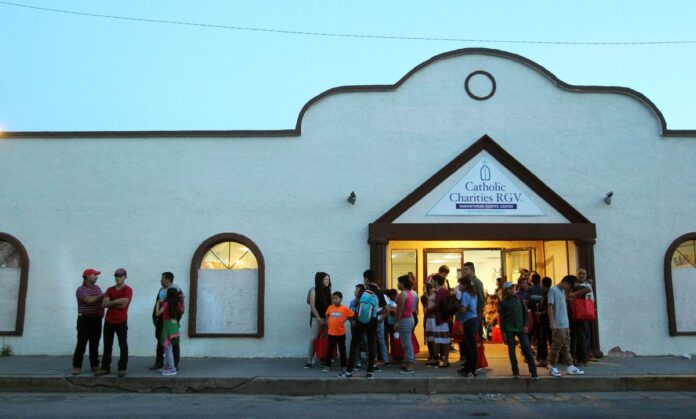 Central American families wait by the entrance of the Catholic Charities Humanitarian Respite Center before boarding a van to be shuttled to a near by church in Alamo to spend the night on Tuesday, June 26, 2018 in McAllen. (Delcia Lopez | dlopez@themonitor.com)